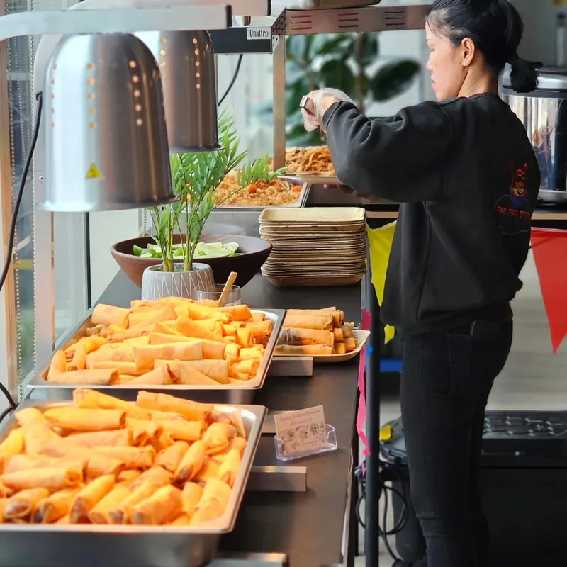 Chef Nok setting out trays of freshly fried spring rolls at an event